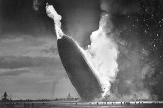 FILE - In this May 6, 1937 file photo, the German dirigible Hindenburg crashes to earth in flames after exploding at the U.S. Naval Station in Lakehurst, N.J. Werner Gustav Doehner, the last survivor of the disaster, died Nov. 8, 2019 at age 90 in Laconia, N.H. Doehner was 8-years old when he boarded the zeppelin in Germany with his parents and older siblings to return from a vacation. (AP Photo/Murray Becker, File)