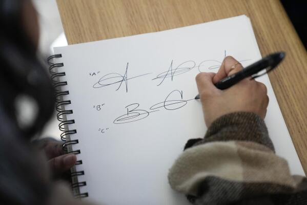 Priscilla Molina creates a custom signature in Los Angeles on Wednesday, Feb. 22, 2023. Molina designs a minimum of 300 custom signatures a month, offering packages that include up to three ways to sign, limitless drafts or a new set of initials. (AP Photo/Ashley Landis)