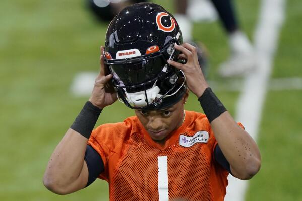 Chicago Bears quarterback Justin Fields puts on his helmet during the NFL football team's voluntary minicamp at Halas Hall in Lake Forest, Ill., Wednesday, April 20, 2022. (AP Photo/Nam Y. Huh)