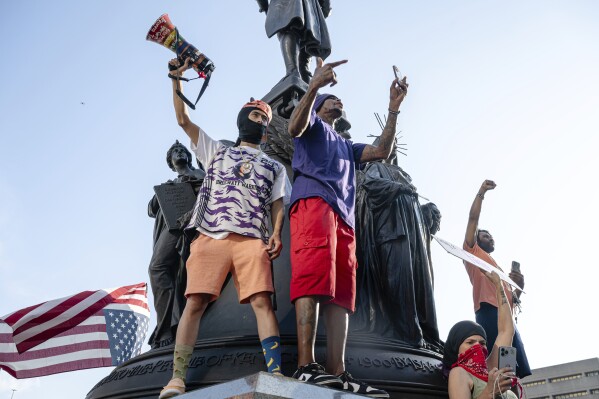 Protesters cheer from statue pedestals during protests against immigration, customs enforcement and the Trump administration in Louisville, Kentucky, Monday, June 9, 2025 (AP Photo/Jon Cherry)