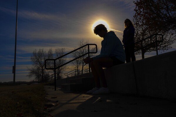 A teenage swimmer and his mother pose at a park near their home about 40 miles north of Denver on Dec. 22, 2023. The Associated Press is not using the teen's name because he is a minor. Another teen accused the swimmer of slapping him on the butt in a locker room in 2021. Police investigated and dismissed the case in a matter of weeks, but the U.S. Center for SafeSport has had an investigation going for more than 20 months, which has cast a shadow over the teenager's promising swimming future. (AP Photo/Jack Dempsey)