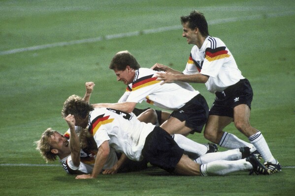 FILE - Germany players celebrate after Andreas Brehme, left on ground, scores the winning goal in the World Cup soccer final match against Argentina, in the Olympic Stadium, in Rome, July 8, 1990. Andreas Brehme, who scored the only goal as West Germany beat Argentina to win the 1990 World Cup final, has died. He was 63. Brehme’s partner Susanne Schaefer has confirmed his death in a statement to Germany’s dpa news agency. (AP Photo/Carlo Fumagalli, File)
