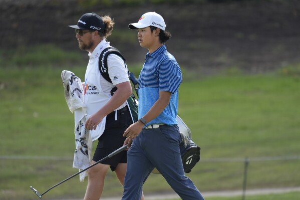 Kris Kim, 16, carries a club as he walks on the 17th green during the first round of the Byron Nelson golf tournament in McKinney, Texas, Thursday, May 2, 2024. (AP Photo/LM Otero)