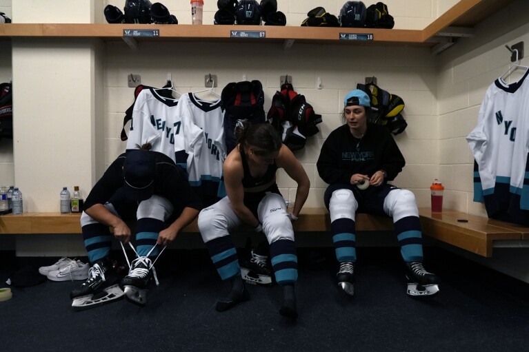 Professional Women's Hockey League New York players get ready in the locker room ahead of the inaugural PWHL game in Toronto, Monday, Jan. 1, 2024. (AP Photo/Brittany Peterson)