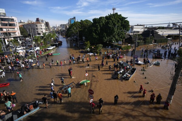 Volunteers gather to help residents evacuate from an area flooded by heavy rain, in Porto Alegre, Brazil, Tuesday, May 7, 2024. (AP Photo/Andre Penner)