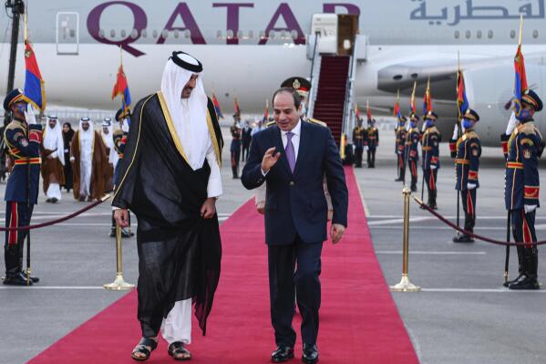 In this photo provided by Egypt's presidency media office, Egyptian President Abdel-Fattah el-Sissi, right, accompanies Qatari Emir Tamim bin Hamad Al Thani upon his arrival at Cairo airport, Egypt, Friday, June 24, 2022. (Egyptian Presidency Media Office via AP)