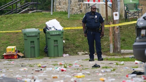 FILE - A police officer stands in the area of a mass shooting incident in the Southern District of Baltimore, Sunday, July 2, 2023. Baltimore leaders are condemning what they called a “catastrophic breakdown” in how city police responded to 911 calls leading up to a mass shooting at a neighborhood block party earlier this month. Police received a call about hundreds of partygoers armed with guns and knives about three hours before the shooting, but on-duty officers decided no law enforcement services were required.(AP Photo/Julio Cortez, File)