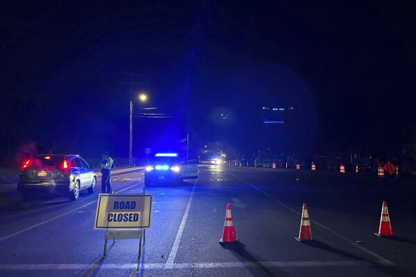 Police block a roadway in Waltham, Mass., after a person in a vehicle struck and injured utility workers before stealing a police cruiser, Wednesday, Dec. 6, 2023. The driver in the suburb of Boston crashed the cruiser before being captured, law enforcement officials said. (APPhoto/Michael Casey)