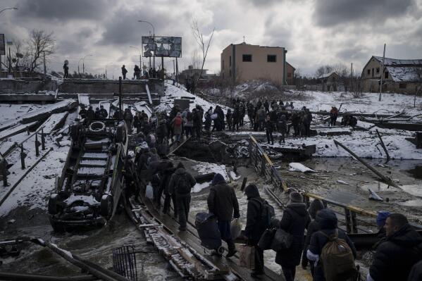 FILE - Ukrainians cross an improvised path under a destroyed bridge while fleeing Irpin, in the outskirts of Kyiv, Ukraine, Tuesday, March 8, 2022. As milestones go, the first anniversary of Russia's invasion of Ukraine is both grim and vexing. It marks a full year of killing, destruction, loss and pain felt even beyond the borders of Russia and Ukraine. (AP Photo/Felipe Dana, File)