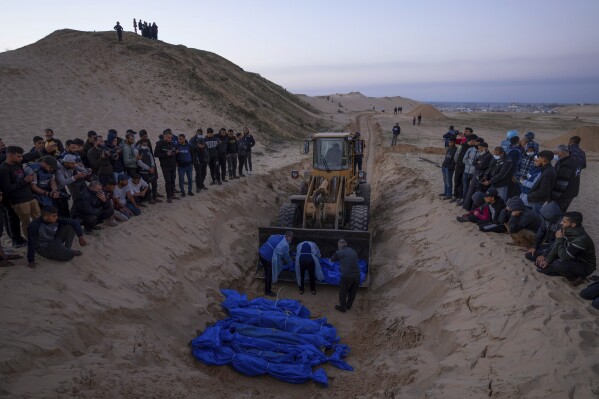 FILE - A bulldozer unloads the bodies of Palestinians killed in Israeli strikes and turned over by the Israeli military during a mass funeral in Rafah, Gaza Strip, Tuesday, Dec. 26, 2023. (AP Photo/Fatima Shbair, File)