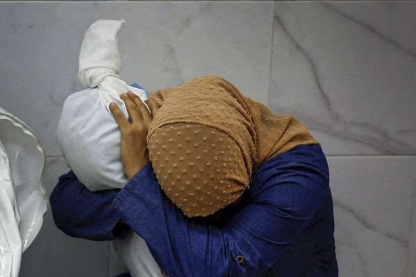 This image provided by World Press Photo and taken by Mohammed Salem of the Reuters news agency won the World Press Photo Award of the Year and shows Palestinian woman Inas Abu Maamar, 36, embracing the body of her 5-year-old niece Saly, who was killed in an Israeli strike, at Nasser hospital in Khan Younis in the southern Gaza Strip, October 17, 2023. (Mohammed Salem/Reuters/World Press Photo via AP)