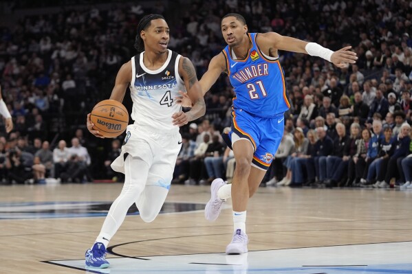 El base de los Minnesota Timberwolves, Rob Dillingham (4), se dirige hacia el aro mientras el base de los Oklahoma City Thunder, Aaron Wiggins (21), defiende durante la primera mitad de un partido de baloncesto de la NBA, el jueves 13 de febrero de 2025, en Minneapolis. (Foto AP/Abbie Parr)