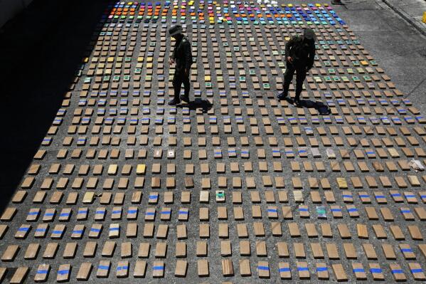 FILE - In this Thursday, Aug. 10, 2017 file photo, police officers walk among packages of seized cocaine at the Pacific port of Buenaventura, Colombia, after about one ton of cocaine was seized in a container during an operation by counternarcotics police at the port. In 2018, Capt. Juan Pablo Mosquera, a Colombian national police officer who was part of an elite unit that worked closely with U.S. anti-narcotics agents, was extradited to Miami to stand trial on charges he betrayed the U.S. Drug Enforcement Administration to the same traffickers they were jointly fighting. (AP Photo/Fernando Vergara)