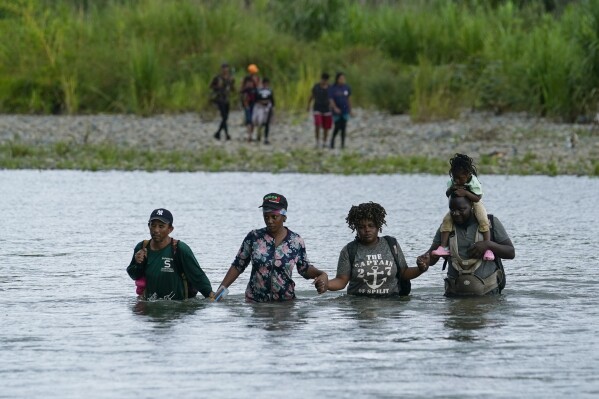 FILE - Haitian migrants wade across the Tuquesa river after trekking through the Darien Gap in Bajo Chiquito, Panama, Wednesday, Oct. 4, 2023. Dozens of charter flights believed to be carrying migrants fleeing crisis-stricken Haiti have touched down in recent days in Nicaragua, the latest in a historic crush of migration to the U.S. (AP Photo/Arnulfo Franco, File)
