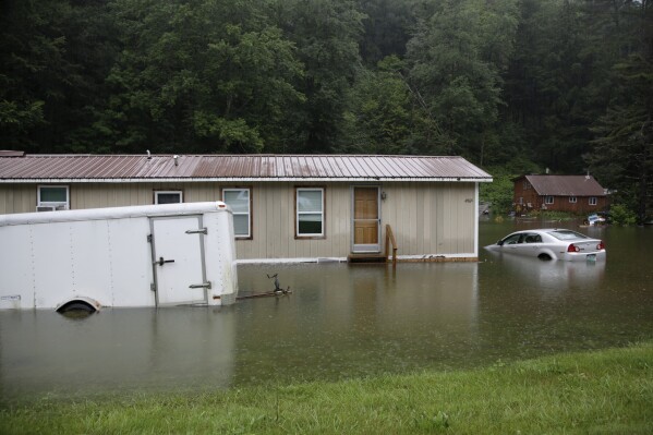FILE - Floodwaters rise, July 10, 2023, in Bridgewater, Vt., submerging parked vehicles and threatening homes near the Ottauquechee River. Americans nationwide face hefty increases in their homeowner’s insurance premiums in the coming years, a report by the First Street Foundation said on Wednesday, Sept. 20, as climate change intensifies floods, wildfires and storms in ways insurance companies are simply unable to keep up with. (AP Photo/Hasan Jamali, File)