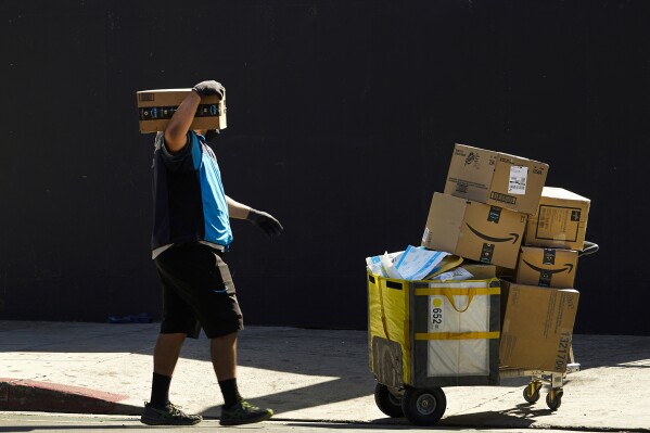 FILE - An Amazon worker delivers packages in Los Angeles on Oct. 1, 2020. July sales events have become a seasonal revenue driver for the retail industry since Amazon launched its first Prime Day back in 2015. (ĢӰԺ Photo/Damian Dovarganes, File)