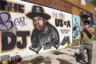 FILE - A pedestrian passes a mural of rap pioneer Jam Master Jay of Run-DMC, by artist Art1Airbrush, Aug. 18, 2020, in the Queens borough of New York. A man charged in the slaying of Jam Master Jay once filmed a brazen rap video in front of a street mural commemorating the Run-DMC legend, prosecutors say in court papers opposing the defendant's release on bail. (AP Photo/John Minchillo, File)