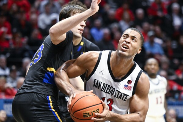 El delantero del estado de San Diego, Jaedon LeDee (13), busca un tiro contra el delantero del estado de San José, Diogo Seixas (23), durante la segunda mitad de un partido de baloncesto universitario de la NCAA el martes, 27 de febrero de 2024, en San Diego.  (Foto AP/Denis Poroy)