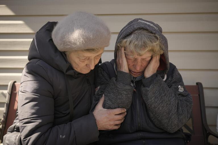 A neighbor comforts Natalia Vlasenko, whose husband, Pavlo Vlasenko, and grandson, Dmytro Chaplyhin, called Dima, were killed by Russian forces, as she cries in her garden in Bucha, Ukraine, Monday, April 4, 2022. Russian soldiers picked up Dima during a Mar. 4 sweep, accused him of being a spotter helping the Ukrainian military and brought him to their headquarters at 144 Yablunska Street. Ukrainian prosecutors now say those responsible for the violence at 144 Yablunska were soldiers from the 76th Guards Airborne Assault Division, under the ultimate battlefield command of Alexander Chaiko, a colonel general known for his brutality as leader of Russia's troops in Syria. (AP Photo/Vadim Ghirda)