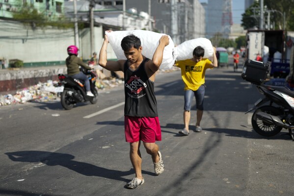 Men deliver sacks of ice cubes as demand remains high due to hot temperatures in Quezon city, Philippines on April 24, 2024. (AP Photo/Aaron Favila, File)