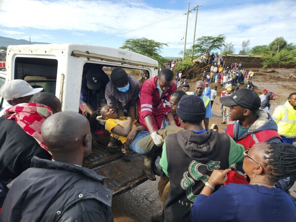 CORRECTS REFERENCE FROM BURST DAM TO BLOCKED TUNNEL - Paramedics carry an injured woman after a river broke through a blocked tunnel causing floodwaters in the Mai Mahiu area of Nakuru County, Kenya, Monday, April. 29, 2024. (AP Photo)