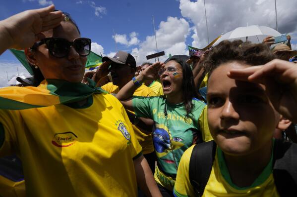 Supporters of Brazilian President Jair Bolsonaro salute and sing their national anthem during a protest against Bolsonaro's run-off election loss outside the Army headquarters in Brasilia, Brazil, Tuesday, Nov. 15, 2022. Bolsonaro supporters are calling for the Armed Forces to intervene in what they call a "fraudulent election." (AP Photo/Eraldo Peres)