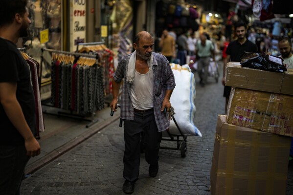 A man pulls a trolley with goods in a street market in Eminonu commercial district in Istanbul, Turkey, Wednesday, Aug. 23, 2023. (AP Photo/Khalil Hamra)