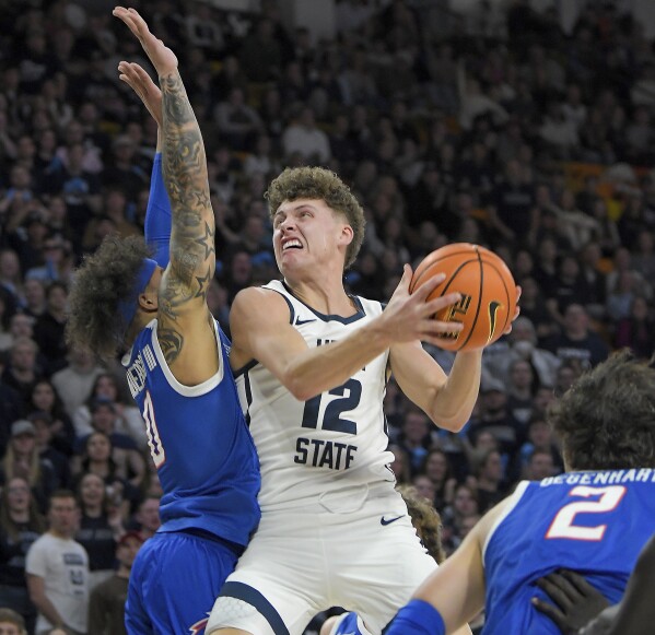 El guardia del estado de Utah, Mason Falslev (12), busca un tiro mientras el guardia del estado de Boise, Roddie Anderson III (0), defiende durante la primera mitad de un partido de baloncesto universitario de la NCAA el sábado 10 de febrero de 2024 en Logan, Utah.  (Eli Lucero/The Herald Journal vía AP)