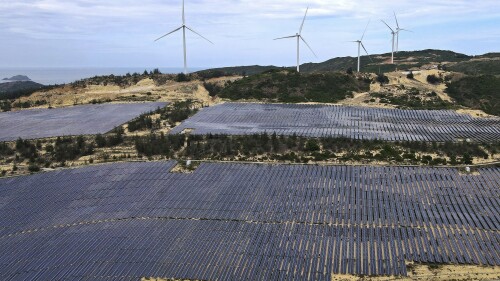 FILE - Solar panels work near wind turbines in Quy Non, Vietnam on June 11, 2023. A human rights advocacy group says it found allegations of dozens of labor and environmental abuses by Chinese-invested companies involved in mining or processing minerals used in renewable energy. (AP Photo/Minh Hoang, File)
