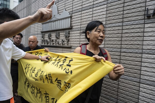 Miembros del Partido Socialdemócrata sostienen una pancarta frente al Tribunal de Magistrados de West Kowloon en Hong Kong, el jueves 30 de mayo de 2024, antes de un fallo en un caso de seguridad nacional.  La pancarta dice "El ejercicio de los derechos constitucionales no es un delito." (Foto AP/Chan Long Hai)