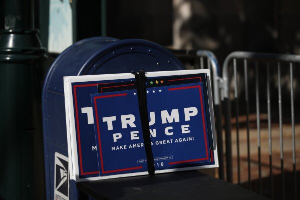 Trump signs sit beside a mailbox as supporters of President Donald Trump set up to protest outside the Pennsylvania Convention Center, where vote counting continues, in Philadelphia, Monday, Nov. 9, 2020, two days after the 2020 election was called for Democrat Joe Biden.(AP Photo/Rebecca Blackwell)