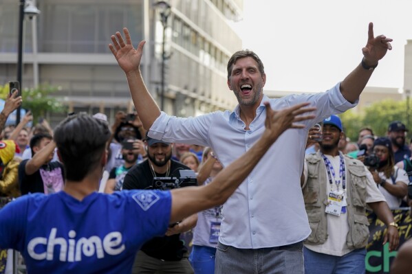 Former Dallas Mavericks player Dirk Nowitzki, right, reacts while performing for fans outside of American Airlines Center prior to Game 3 of the NBA basketball finals between the Mavericks and the Boston Celtics, Wednesday, June 12, 2024, in Dallas. (AP Photo/Sam Hodde)