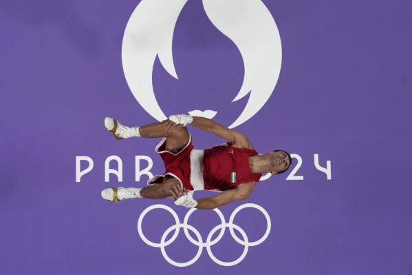 Uzbekistan's Abdumalik Khalokov celebrates with a backflip after defeating Spain's Jose Quiles in their men's 57kg quarterfinal boxing match at the 2024 Summer Olympics, Saturday, Aug. 3, 2024, in Paris, France. (AP Photo/John Locher)