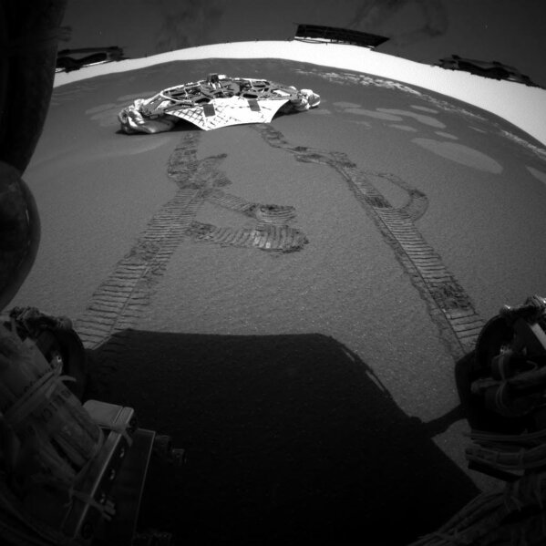 
              FILE - This photo released Thursday, Feb. 5, 2004 made by one of the rear hazard-avoidance cameras on NASA's Opportunity rover, shows Opportunity's landing platform, with freshly made tracks leading away from it. Opportunity rolled about 11 feet on Thursday, the first day it has moved since it left the lander on Saturday. Engineers commanded Opportunity to turn slightly during the drive, to test how it steers while rolling through the martian soil. (NASA/JPL via AP)
            