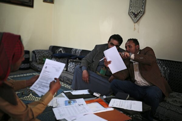 Mohammed Al Zabidi, right, shows paperwork from his canceled U.S. visa to his brother at his home in Sanaa, Yemen, Thursday, Jan. 28, 2021. The Trump administration’s travel ban that affected several Muslim-majority nations robbed him of his American dream and his chance to escape his war-torn homeland. With a new president at the helm, the ban is over, but Al Zabidi’s plight isn’t. (AP Photo/Hani Mohammed)