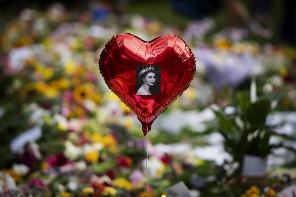 A balloon with a picture of Queen Elizabeth II is photographed at the Green Park memorial, near Buckingham Palace, in London, Saturday, Sept. 10, 2022. Queen Elizabeth II, Britain's longest-reigning monarch and a rock of stability across much of a turbulent century, died Thursday Sept. 8, 2022, after 70 years on the throne. She was 96. (AP Photo/Emilio Morenatti)