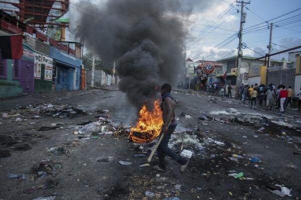 A man walks past burning tires set up by protesters during a protest demanding the resignation of Prime Minister Ariel Henry in the Delmas area of Port-au-Prince, Haiti, Monday, Oct. 10, 2022. (AP Photo/Odelyn Joseph)