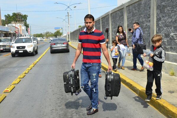 The Ascencio family, from Venezuela, carry their luggage after being returned by U.S. authorities to Nuevo Laredo, Mexico as part of the first group of migrants to be sent back to Tamaulipas state under the so-called Remain in Mexico program for U.S. asylum seekers, Tuesday, July 9, 2019. Approximately 10 migrants crossed the border Monday to seek U.S. asylum and were sent back on Tuesday to wait as their applications are processed. (AP Photo/Salvador Gonzalez)