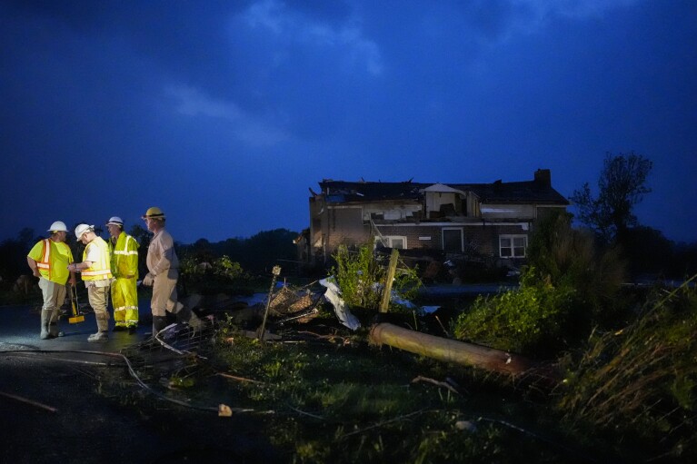 Utility workers survey storm damage along Cothran Road, Wednesday, May 8, 2024, in Columbia, Tenn. (AP Photo/George Walker IV)