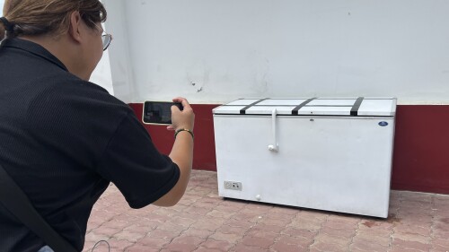 A Thai reporter takes a photo of an empty freezer at the Nong Prue police station in Pattaya, Chonburi province, Thailand, Tuesday, July 11, 2023. The dismembered body of a 62-year-old German businessman Hans-Peter Mack who has been missing for a week has been found in the freezer of a house in southern Thailand, police said Tuesday. (AP Photo)