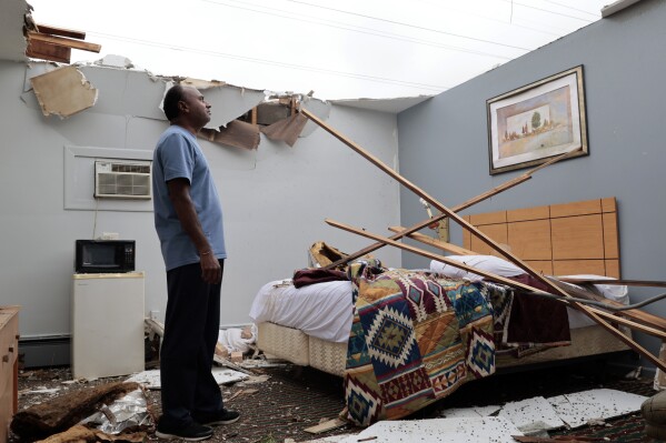 With the roof blown off by severe winds, Brian Patel, owner of the Skyline Motel in the suburban town of McCook, Ill., for the past 30 years, surveys storm damage in one of the motel rooms, Thursday, July 13, 2023. (Antonio Perez/Chicago Tribune via AP)