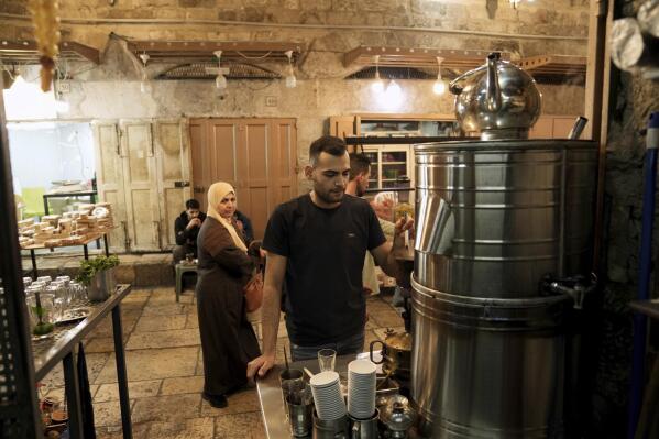Majd Ramlawi works in a cafe at the Cotton Merchants' Market near the entrance to the Al-Aqsa Mosque compound in the Old City of Jerusalem, Nov. 7, 2022. Ramlawi was serving coffee in Jerusalem’s Old City when a chilling text message appeared on his phone. “You have been spotted as having participated in acts of violence in the Al-Aqsa Mosque,” it read in Arabic. “We will hold you accountable.” Ramlawi, then 19, was among hundreds of people whom civil rights attorneys estimate got the text the previous year at the height of one of the most turbulent recent periods in the Holy Land. (AP Photo/Mahmoud Illean)