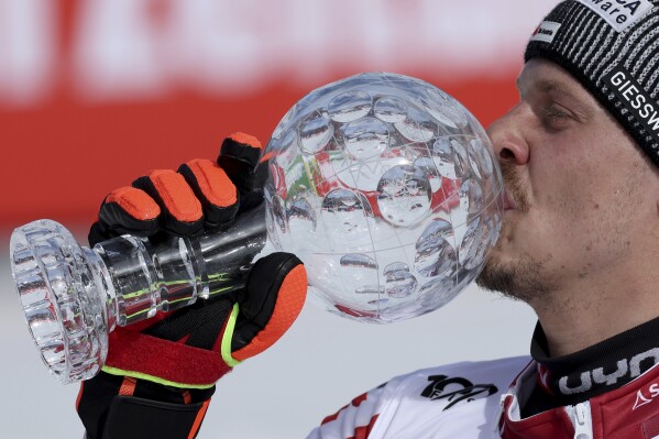 Austria's Manuel Feller kisses the trophy for the alpine ski, men's World Cup slalom discipline, in Saalbach, Austria, Sunday, March 17, 2024. (AP Photo/Marco Trovati)