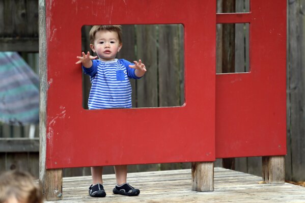 FILE - In this Aug. 27, 2018, Vincent Seeborn, 2, reaches out from a structure on the playground at the Wallingford Child Care Center in Seattle. Child care costs in most states exceed federal subsidy payments provided to low-income parents, according to a newly released report from the Department of Health and Human Services Office of Inspector General, leaving working families with few affordable options. (AP Photo/Elaine Thompson, File)