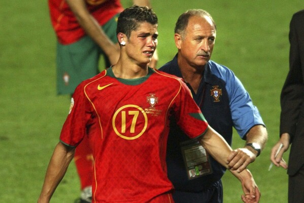 FILE - Portugal coach Luiz Felipe Scolari, right, leads a tearful Cristiano Ronaldo to collect his runners-up medal after Greece beat Portugal 1-0 in the Euro 2004 soccer championship final match at the Luz stadium in Lisbon, Portugal, Sunday, July 4, 2004. Portugal's Cristiano Ronaldo and Croatia's Modric go to Euro 2024 showing age is no boundary for soccer's modern stars. (AP Photo/Luca Bruno, File)