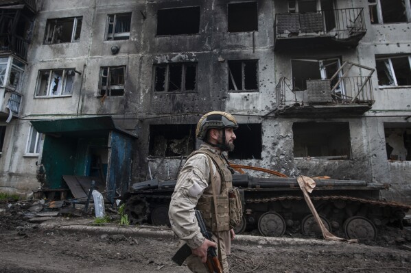 FILE - A Ukrainian soldier passes by a damaged apartment building in Chasiv Yar, the site of heavy battles with the Russian forces in the Donetsk region, Ukraine, Tuesday, May 9, 2023. (Iryna Rybakova via AP, File)