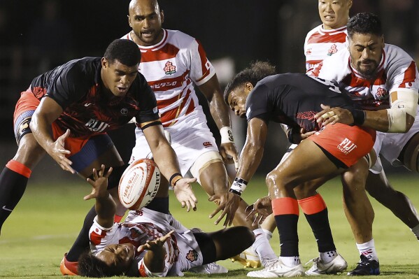 Kotaro Matsushima of Japan tried to pass the ball against Simione Kuruvoli, right, of Fiji during a Pacific Nations Cup rugby match in Tokyo, Japan, Saturday, Aug. 5, 2023. (Kyodo News via AP)