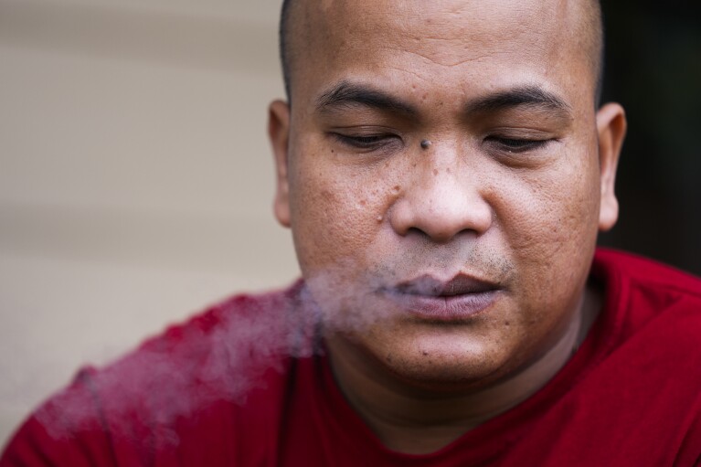 Seafarer Richard Zambales, from the Philippines, smokes outside a temporary rental house in Lacey, Wash., on Tuesday, Jan. 30, 2024. (AP Photo/Lindsey Wasson)