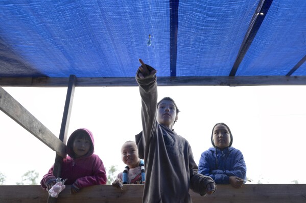 Noah Wassilie, 10, throws a magnetic dart inside a game station at the village carnival, Thursday, Aug. 17, 2023, in Akiachak, Alaska. The village hosted a multiday carnival with games and prizes for the village youth. (AP Photo/Tom Brenner)