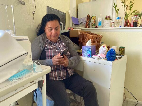 Rosalidia Dardon, 54, looks at a picture of her daughter in El Salvador as she sits in a refugee house in Texas, awaiting asylum or a protected immigration status on Nov. 4, 2021. At least seven statehouses have considered or left pending legislation this year to replace the term “illegal,” “alien,” or both from state laws referencing immigrants. Dardon knows from personal experience why the language surrounding immigration is so important. (Acacia Coronado/Report for America via AP)
